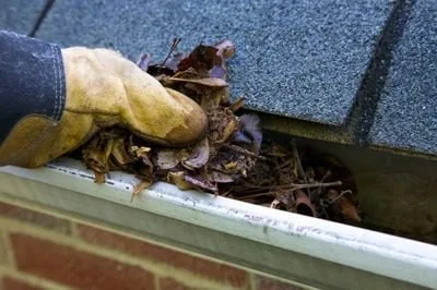 Gutter Solutions of Texas worker cleaning residential gutter with water hose.